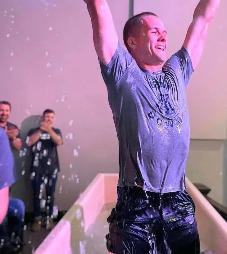 Tyler with hands raised after being baptized